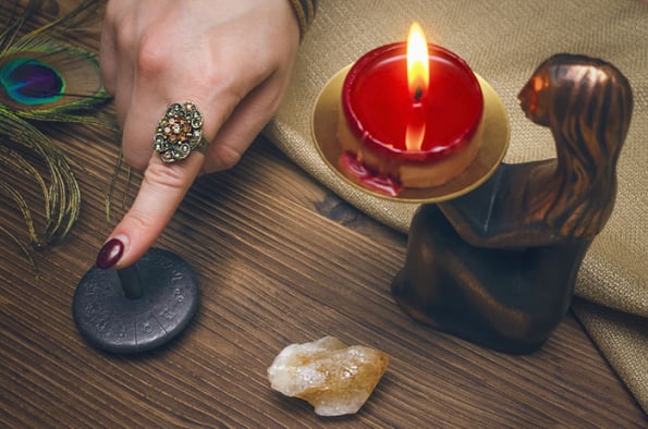 Divination pendulum and candle on a wooden table